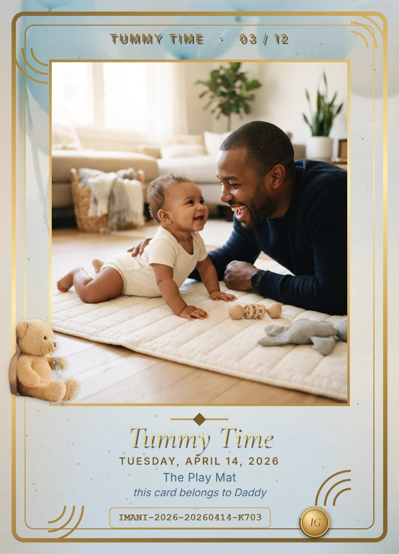 A three-month-old baby girl on a play mat laughing with her father, on a baby blue keepsake card with a teddy bear holding blue balloons sitting on the corner of the photo